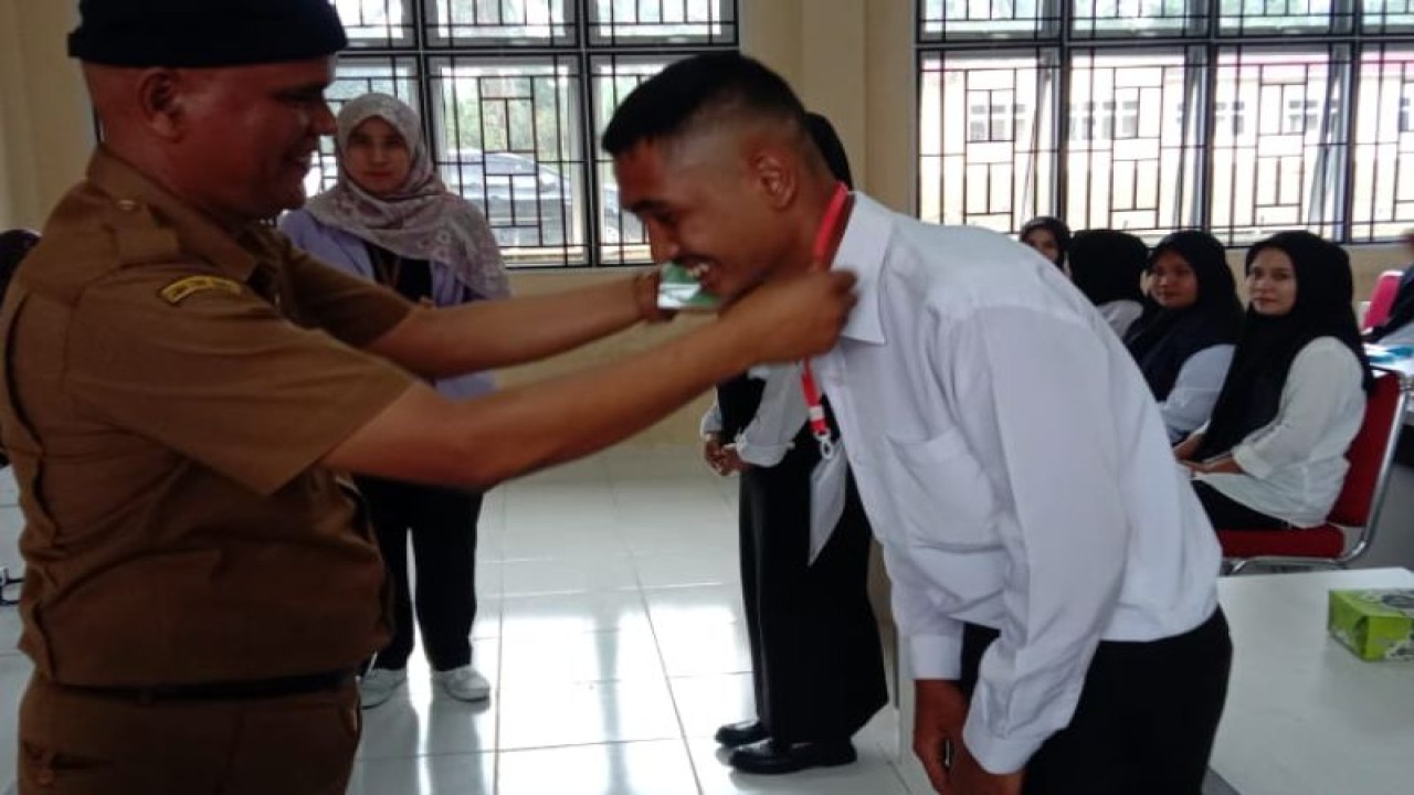 Kepala Dinas Tenaga Kerja Pasaman Barat Armen saat memasangkan tanda pengenal terhadap salah seorang peserta pelatihan berbasis kompotensi di BLK setempat.