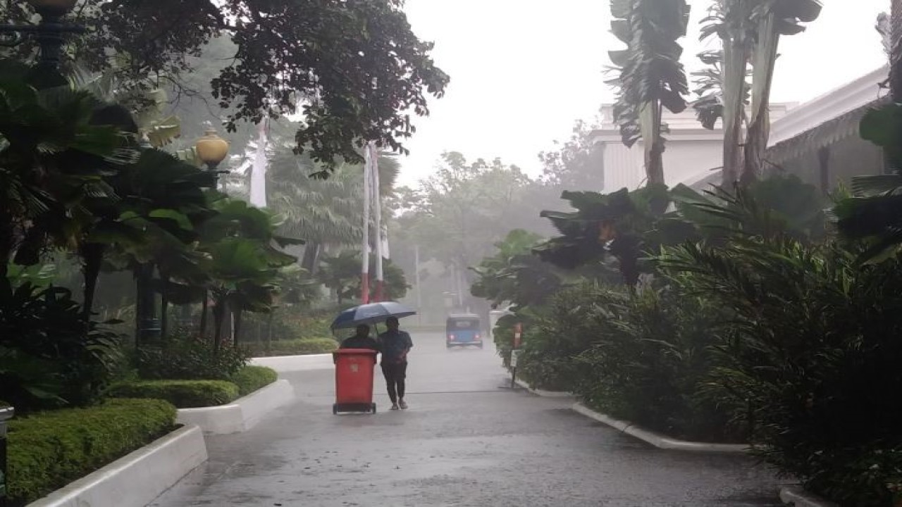 Petugas di Balai Kota Jakarta berjalan menggunakan payung di tengah hujan deras mengguyur Jakarta, Jumat (24/2/2023).ANTARA/Dewa Ketut Sudiarta Wiguna.