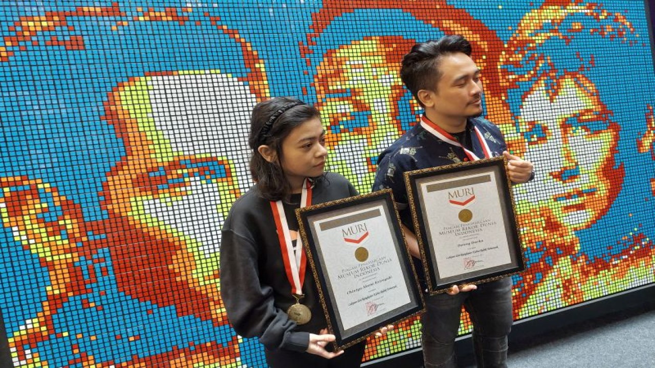 Pesulap Denny Darko dan Chintya Akemi Keirayuki menunjukkan penghargaan Museum Rekor Dunia Indonesia (MURI) atas karya lukisan dari rangkaian kubus rubik terbanyak bergambar tokoh pemeran film produksi Marvel Studios yaitu Ant-Man and The Wasp : Quantumania. (ANTARA/Adimas Raditya)