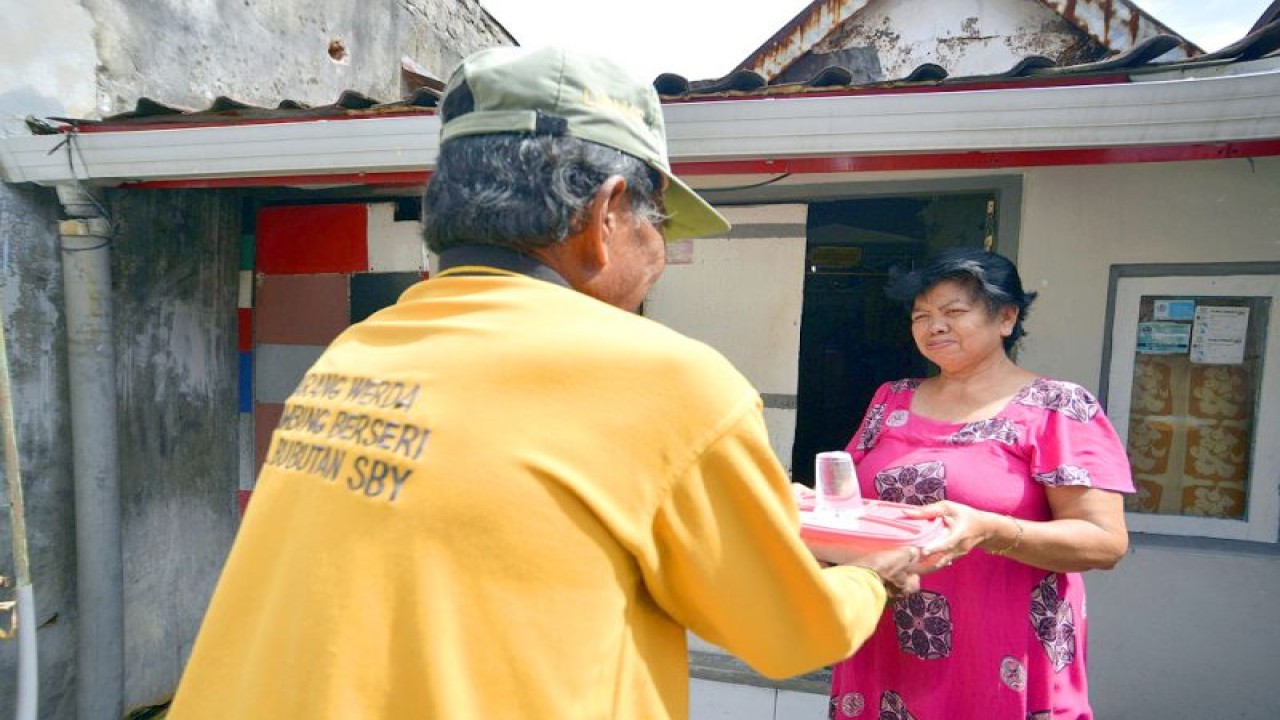 Salah seorang petugas Dinas Sosial memberikan bantuan makanan kepada lansia di Kota Surabaya. ANTARA/HO-Diskominfo Surabaya