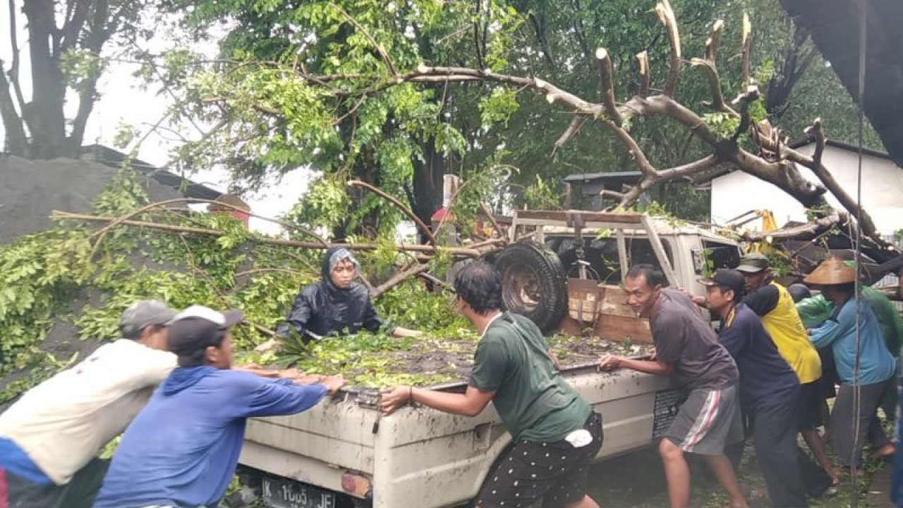 Warga secara bergotong royong mendorong mobil bak terbuka yang tertimpa pohon saat hendak mengantarkan pasir ke pelanggan di tepi Jalan Lingkar Panjang, Desa Peganjaran, Kecamatan Bae, Kabupaten Kudus, Jawa Tengah, Senin (27/2/2023). (ANTARA/Akhmad Nazaruddin Lathif)