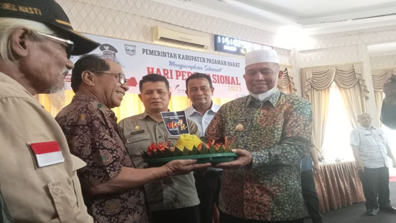 Bupati Pasaman Barat Hamsuardi saat menyerahkan tumpeng kepada Yulison, salah seorang perwakilan wartawan saat peringatan dan syukuran HPN 2023 di Simpang Empat, Sumbar, Kamis (9/2/2023). ANTARA/Altas Maulana