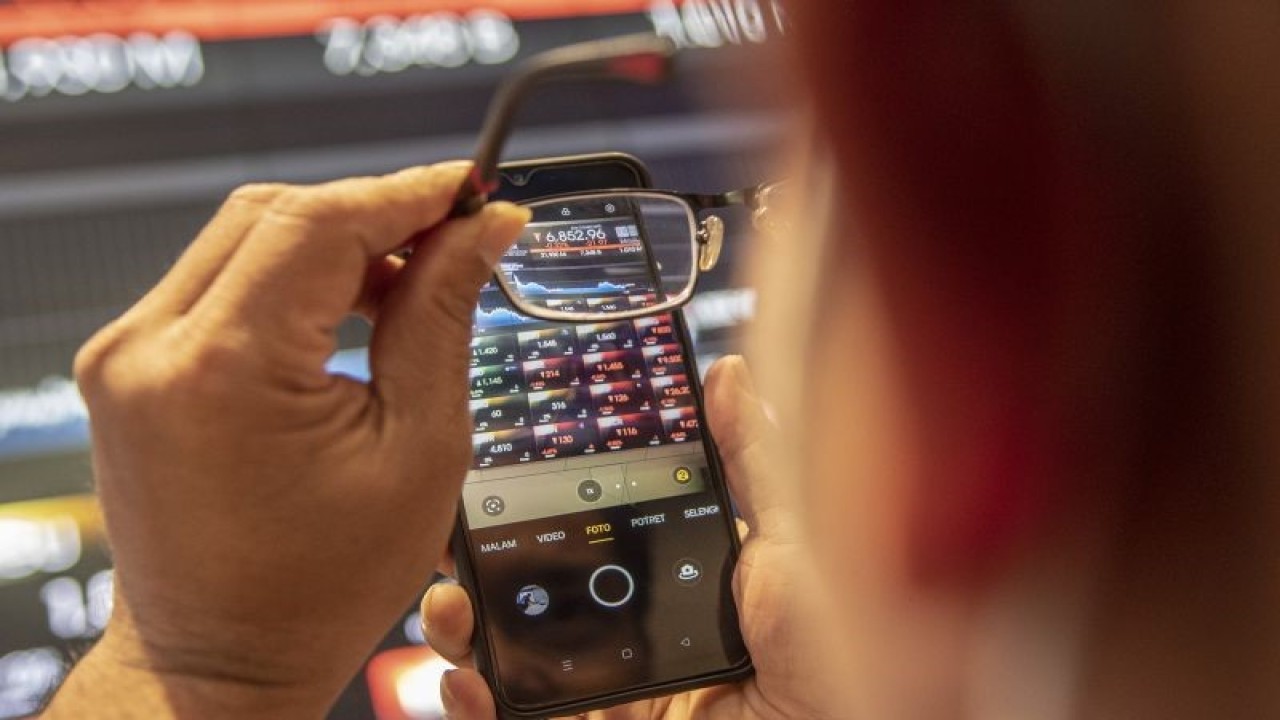Karyawan mengambil gambar menggunakan ponselnya layar yang menunjukkan pergerakan Indeks Harga Saham Gabungan (IHSG) di Bursa Efek Indonesia, Jakarta, Selasa (24/1/2023). ANTARA FOTO/Muhammad Adimaja/aww.
