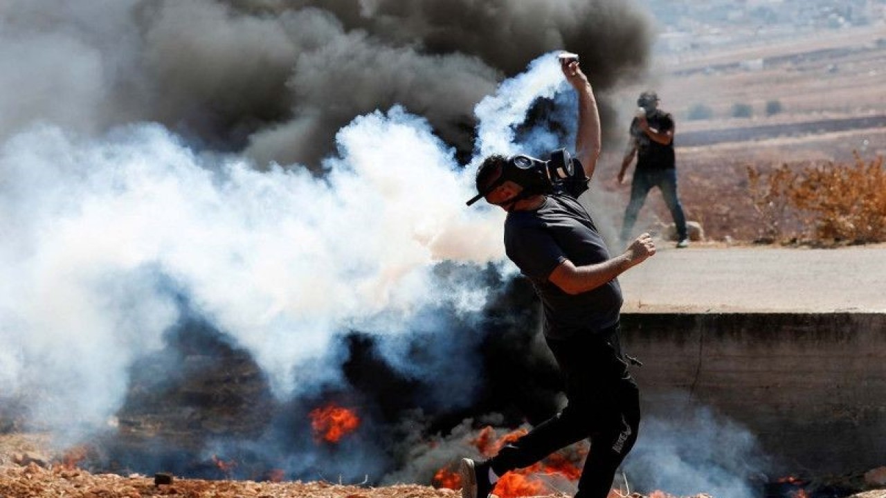 Arsip - Pengunjuk rasa Palestina mengembalikan kaleng gas airmata yang ditembakkan polisi Israel, pada aksi protes menentang pemukiman Israel, di Beit Dajan, wilayah pendudukan Tepi Barat, Jumat (22/10/2021). REUTERS/Mohamad Torokman/AWW/djo (REUTERS/MOHAMAD TOROKMAN)