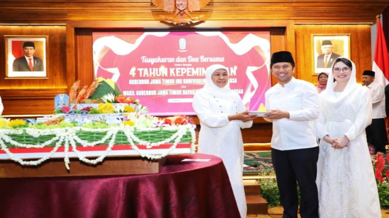 Gubernur Khofifah Indar Parawansa menyerahkan potongan tumpeng kepada Wakil Gubernur Emil Elestianto Dardak (tengah) yang didampingi istri Arumi Bachsin menandai empat tahun masa kepemimpinannya di Pemprov Jatim, Senin (13/2/2023). (ANTARA/HO-Biro Adpim Jatim)