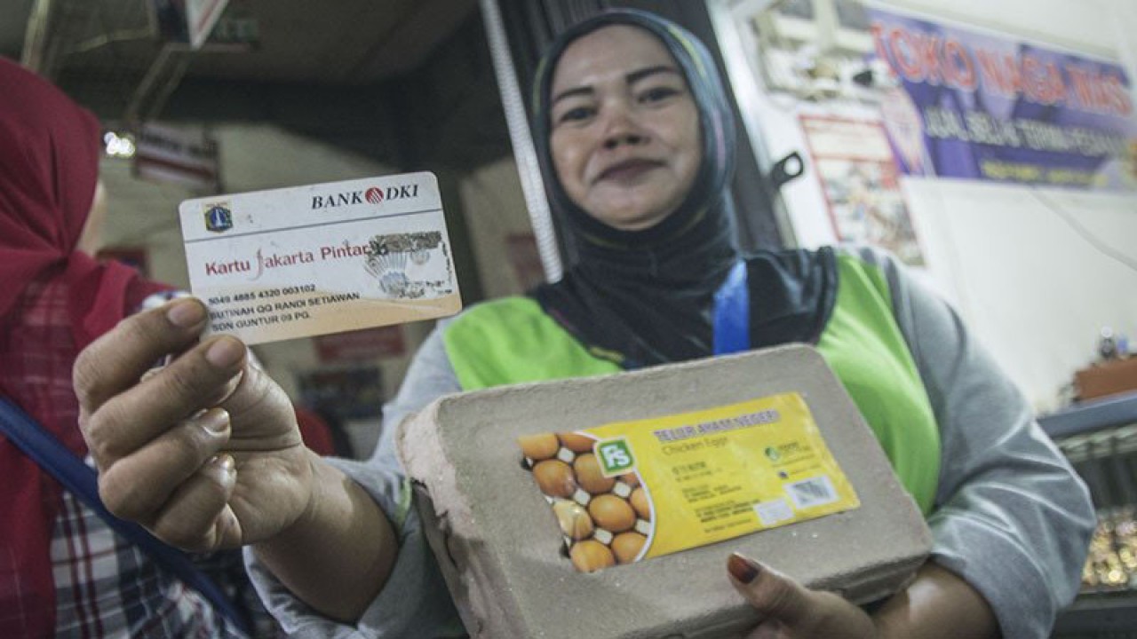 Warga menunjukan Kartu Jakarta Pintar (KJP) seusai berbelanja kebutuhan pokok menggunakan kartu tersebut di Pasar Rumput, Jakarta, Kamis (8/2/2018). ANTARA FOTO/Aprillio Akbar/pd.