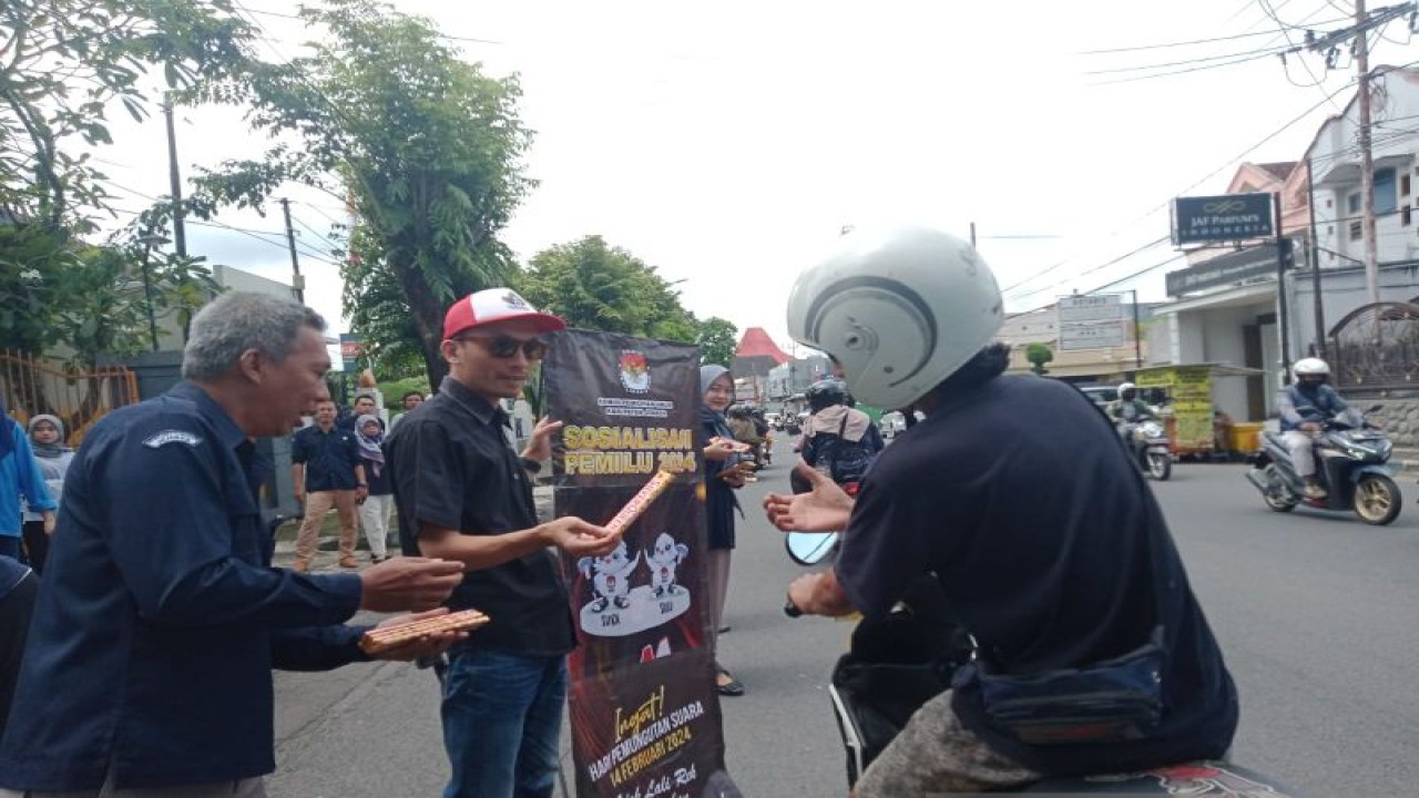 Anggota KPU Jember Andi Wasis (kiri) bersama staf menyosialisasikan Pemilu 2024 sambil membagikan coklat kepada pengendara yang melintas di depan Kantor KPU Jember, Selasa (14/2/2023). ANTARA/Zumrotun Solichah