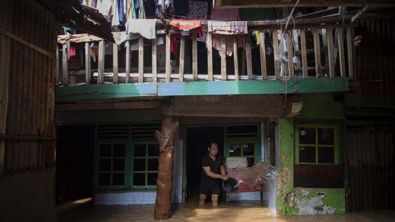 Warga membersihkan tembok rumahnya saat banjir di Taman Harapan, Cawang, Kramat Jati, Jakarta Timur, Rabu (12/10/2022). ANTARA FOTO/Sigid Kurniawan/aww.