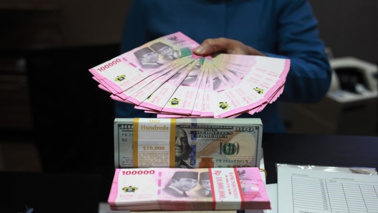 Petugas menunjukkan uang dolar AS dan uang rupiah di salah satu kantor cabang PT. Bank Mandiri Persero Tbk, Jakarta, Selasa (31/1/2023). ANTARA FOTO/Reno Esnir/tom.