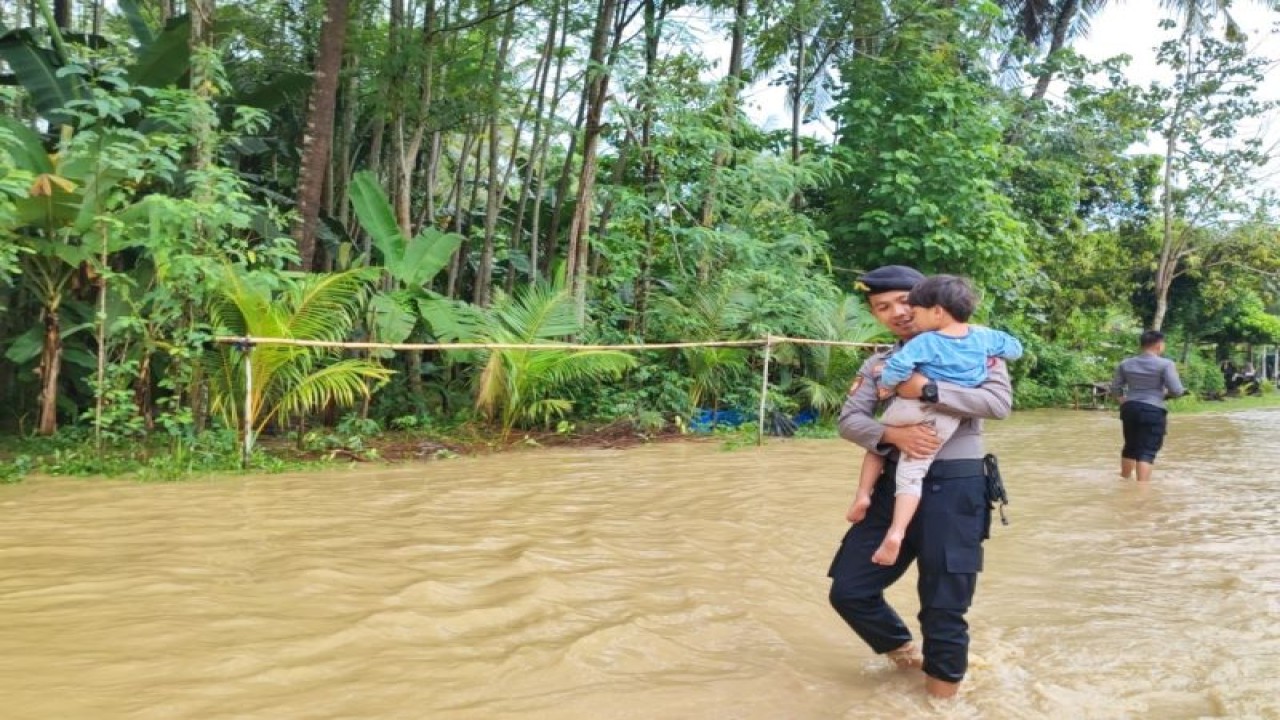 Seorang anggota polisi menggendong anak yang terdampak banjir di Kecamatan Sekotong, Kabupaten Lombok Barat, Nusa Tenggara Barat, Senin (13/2/2023). ANTARA/HO-Polres Lobar