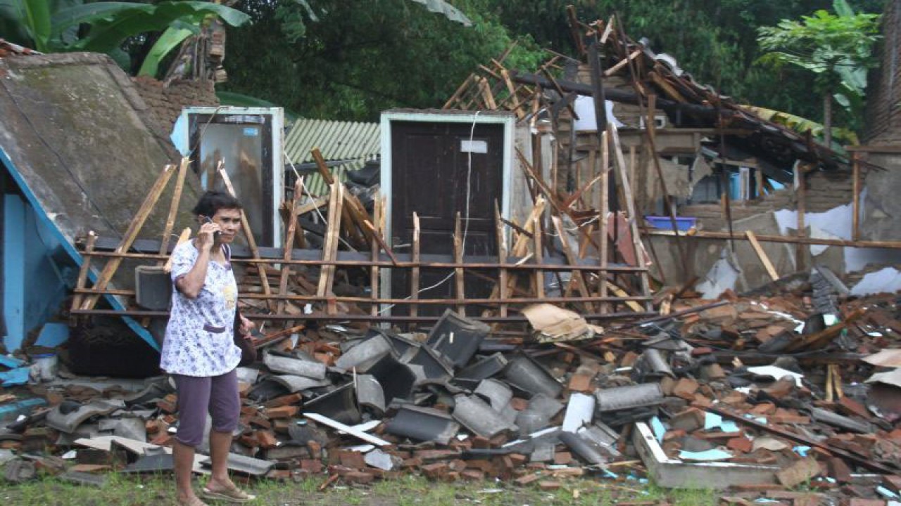 Arsip Foto. Seorang warga menelepon di depan rumahnya yang hancur akibat gempa di Majangtengah, Kabupaten Malang, Jawa Timur, Minggu (11/4/2021). (ANTARA FOTO/Ari Bowo Sucipto)