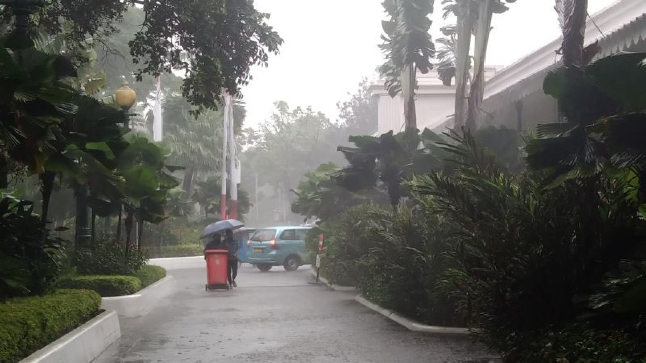 Pegawai di Balai Kota Jakarta berjalan menggunakan payung di tengah hujan deras melanda Jakarta, Jumat (24/2/2023) ANTARA/Dewa Ketut Sudiarta Wiguna