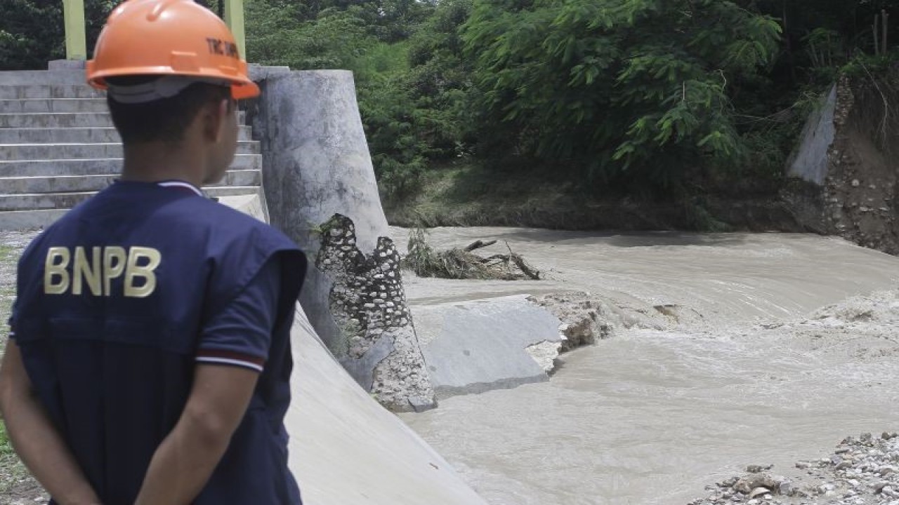 Seorang petugas Badan Penangulanggan Bencana (BNPB) memantau pintu air bendungan Oesao yang jebol akibat cuaca ekstrem berupa hujan yang terjadi di daerah itu Minggu (5/2/2023). ANTARA FOTO/Kornelis Kaha