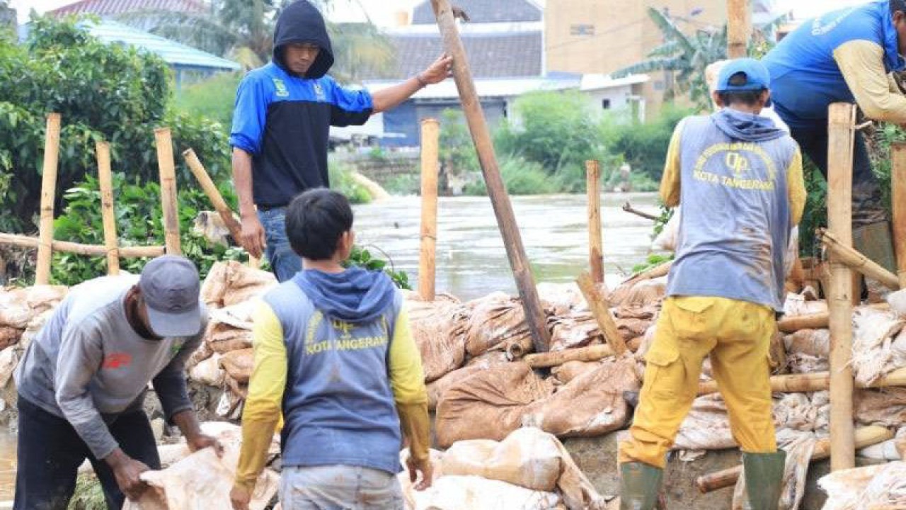 Petugas PUPR sedang membuat kisdam dalam mengatasi luapan air dari kali