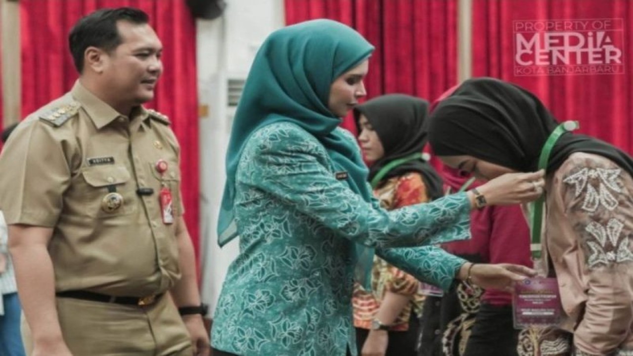 Wali Kota Banjarbaru M Aditya Mufti Ariffin mendampingi Ketua TP PKK Vivi Mar'i Zubedi memasang tanda peserta sekolah gratis yang digelar untuk memberdayakan perempuan di kota setempat. ANTARA/HO-Kominfo Banjarbaru.