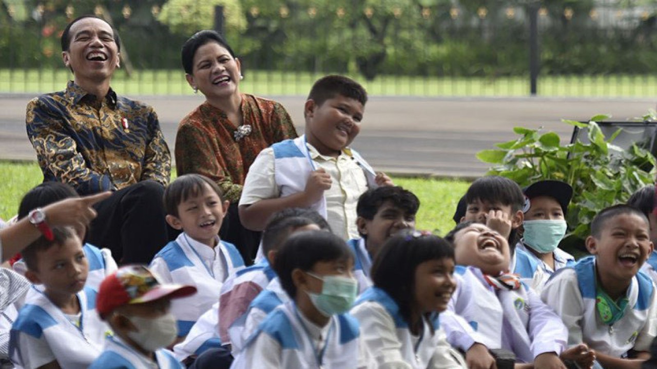 Presiden Joko Widodo (kiri) didampingi Ibu Negara Iriana Joko Widodo dan anak-anak penderita kanker pendampingan Yayasan Kanker Anak Indonesia tertawa saat menyaksikan pertunjukan sulap disela-sela silaturahmi di halaman belakang Istana Bogor, Jawa Barat, Jumat (6/4). Yayasan Kanker Anak Indonesia dalam kesempatan tersebut meminta regulasi impor obat kanker dipermudah dan bea masuk ditiadakan. ANTARA FOTO/Puspa Perwitasari/ama. (ANTARA FOTO/PUSPA PERWITASARI)