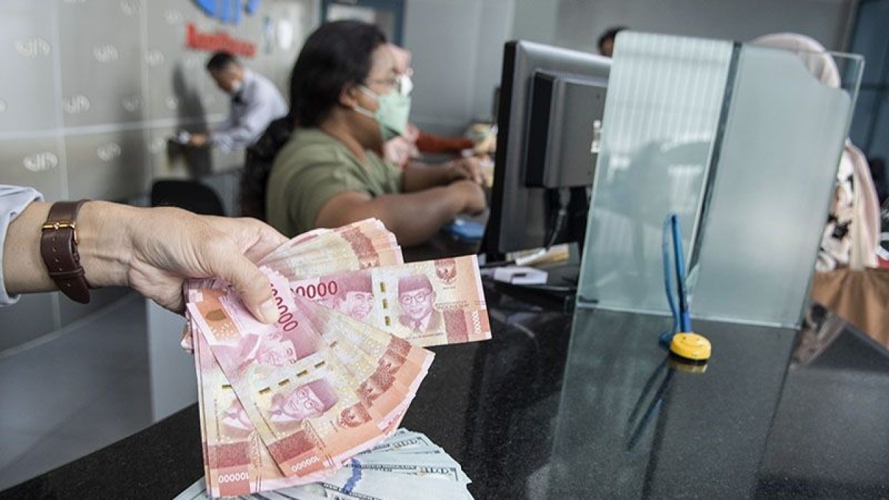 Petugas menunjukan uang pecahan rupiah dan dolar AS di gerai penukaran mata uang asing VIP (Valuta Inti Prima) Money Changer, Jakarta, Selasa (3/1/2023). ANTARA FOTO/Muhammad Adimaja/foc/aa.