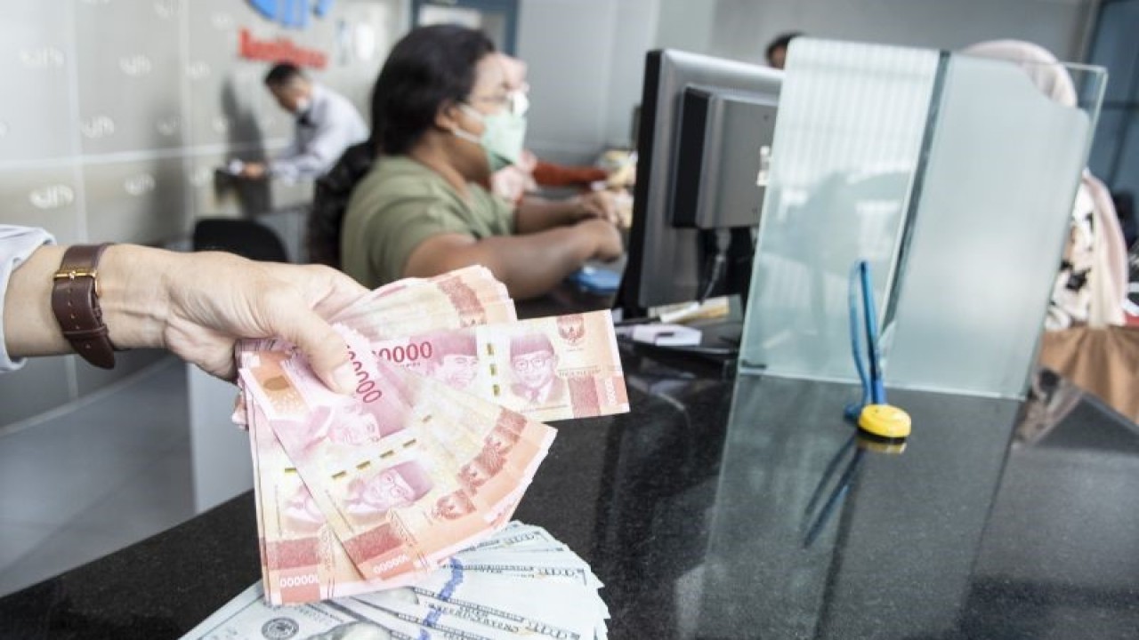 Petugas menunjukan uang pecahan rupiah dan dolar AS di gerai penukaran mata uang asing VIP (Valuta Inti Prima) Money Changer, Jakarta, Selasa (3/1/2023). ANTARA FOTO/Muhammad Adimaja/foc.