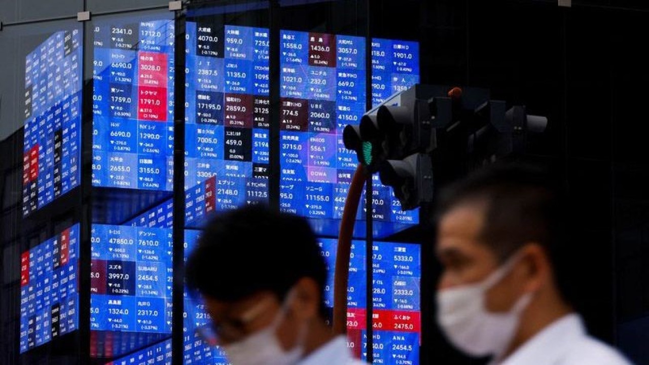 Arsip Foto - Orang-orang melewati layar elektronik yang menunjukkan indeks harga saham Nikkei Jepang di dalam sebuah aula konferensi di Tokyo, Jepang. ANTARA/REUTERS/Issei Kato/am.