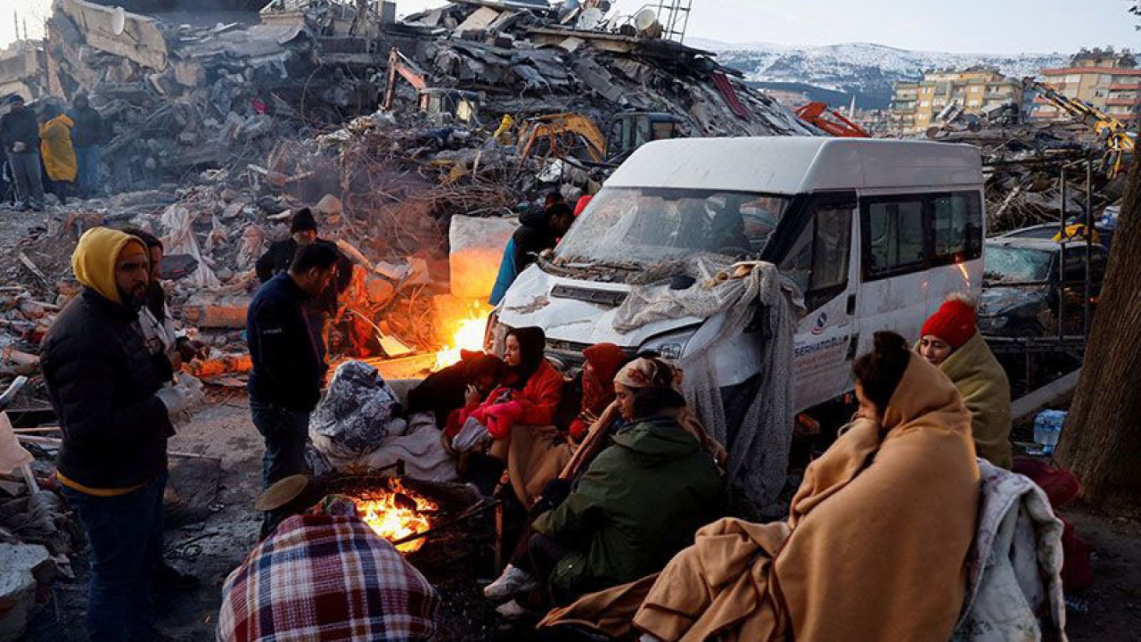 Ilustrasi: Orang-orang duduk di sekitar api di samping puing-puing dan kerusakan di dekat lokasi bangunan yang runtuh setelah gempa bumi, di Kahramanmaras, Turki, 8 Februari 2023. ANTARA/REUTERS/Suhaib Salem/pri. (REUTERS/SUHAIB SALEM)
