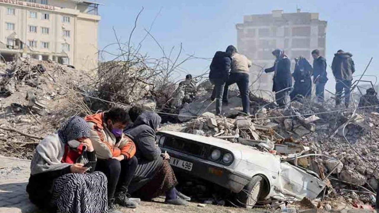 Warga duduk di dekat reruntuhan bangunan terdampak gempa di Kahramanmaras, Turki, Selasa (14/2/2023). ANTARA FOTO/REUTERS/Nir Elias/rwa.