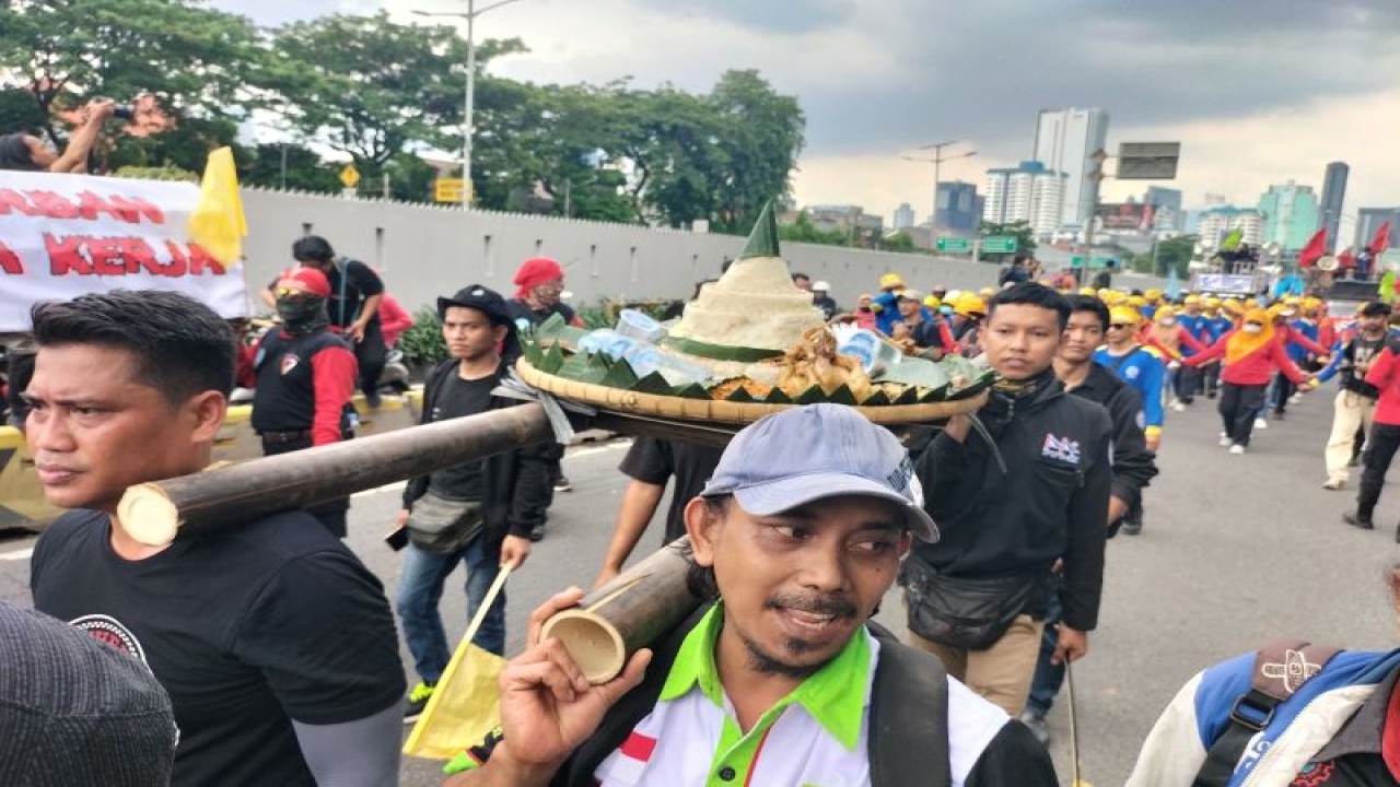 Buruh bawa nasi tumpeng dalam aksi unjuk rasa di depan Dedung DPR RI, Selasa (28/02/2023) ANTARA/Walda