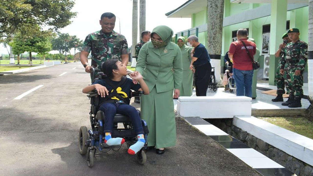 Danrem 071/Wijayakusuma Kolonel Inf Yudha Airlangga didampingi istri mendorong kursi roda adaptif yang digunakan salah seorang anak penyandang disabilitas ganda penerima bantuan di halaman Gedung Pertemuan A. Yani, Markas Korem 071/Wijayakusuma, Sokaraja, Kabupaten Banyumas, Senin (6/2/2023). FOTO ANTARA/HO-Penrem Wijayakusuma
