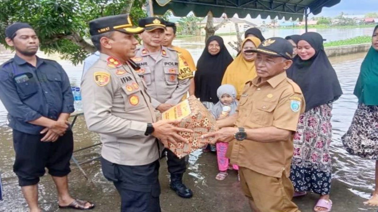 Kapolres Banjar AKBP M Ifan Hariyat menyerahkan bantuan paket sembako bagi warga terdampak banjir di Kecamatan Martapura Barat yang diterima simbolis oleh Pembakal Desa Teluk Selong Mahyani. (ANTARA/Firman)