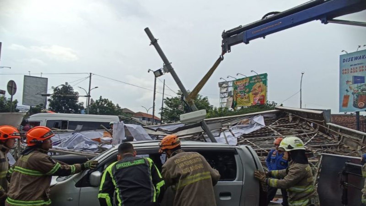 Petugas membersihkan material baliho yang roboh di Simpang Samsat, Jalan Soekarno Hatta, Kota Bandung, Jawa Barat, Sabtu (25/3/2023). (ANTARA/Bagus Ahmad Rizaldi)