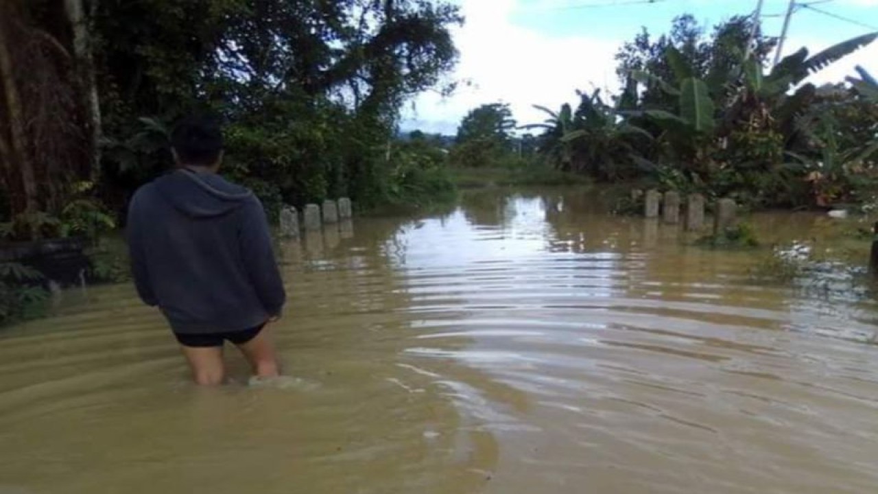 Salah seorang warga Desa Pasir Putih, Kecamatan Pamona Selatan, Kabupaten Poso berjalan di genangan air akibat luapan air sungai desa setempat, Selasa (14/3/2023). ANTARA/HO-BPBD Poso
