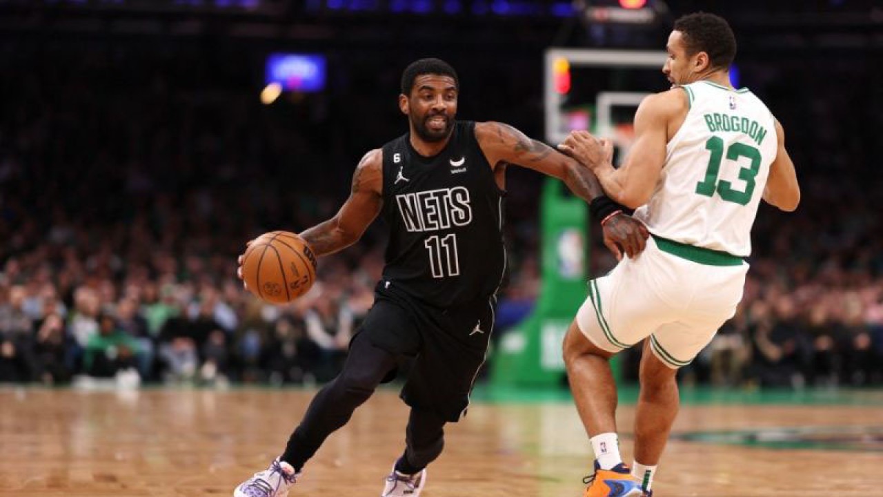 Kyrie Irving (kiri) saat memperkuat Brooklyn Nets menggiring bola melewati Malcolm Brogdon dari Boston Celtics selama paruh pertama di TD Garden pada 01 Februari 2023 di Boston, Massachusetts. ANTARA/Getty Images via AFP/MADDIE MEYER.