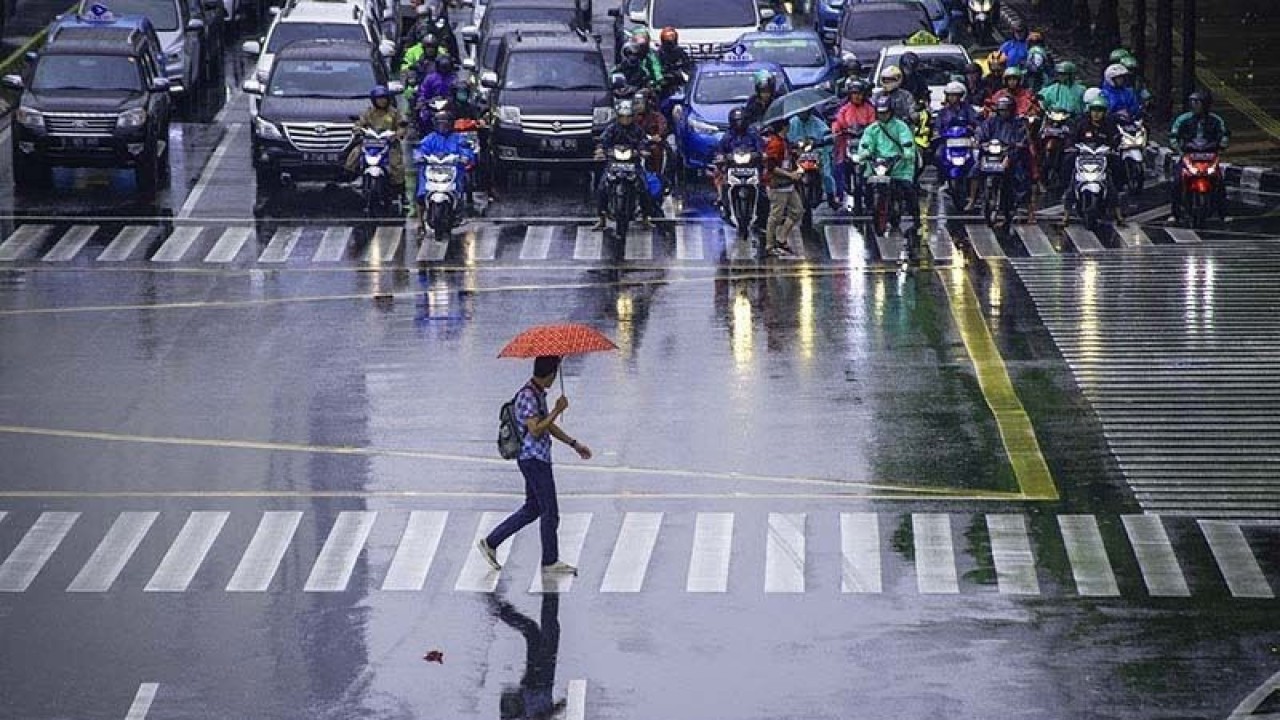Arsip Foto - Seorang pekerja menggunakan payung untuk menghindari hujan saat menyeberang jalan di kawasan Jalan MH Thamrin, Jakarta. (ANTARA/Aprillio Akbar/hp/aa).