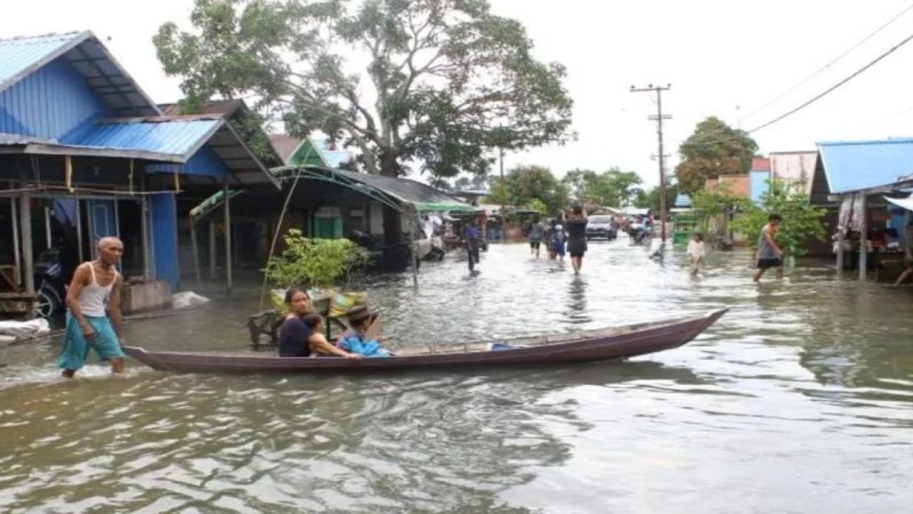 Warga menggunakan perahu melintasi jalan yang terendam banjir di Desa Sungai Rangas Ulu, Kabupaten Banjar, Kalimantan Selatan, Sabtu (4/3/2023). ANTARA/Bayu Pratama