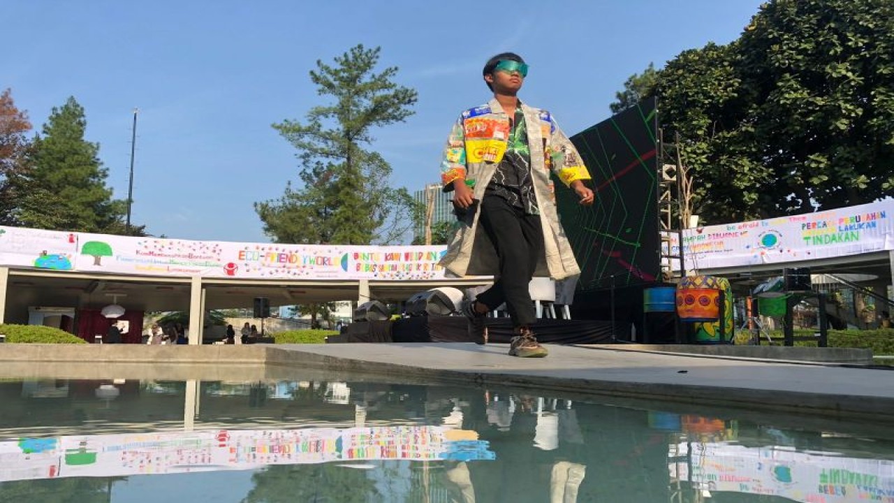 Seorang pelajar menampilkan rancangan busana yang terbuat dari daur ulang sampah anorganik di Taman Literasi Martha Chistina Tiahahu, Jakarta Selatan, Sabtu (18/3/2023). (ANTARA/Sugiharto Purnama)