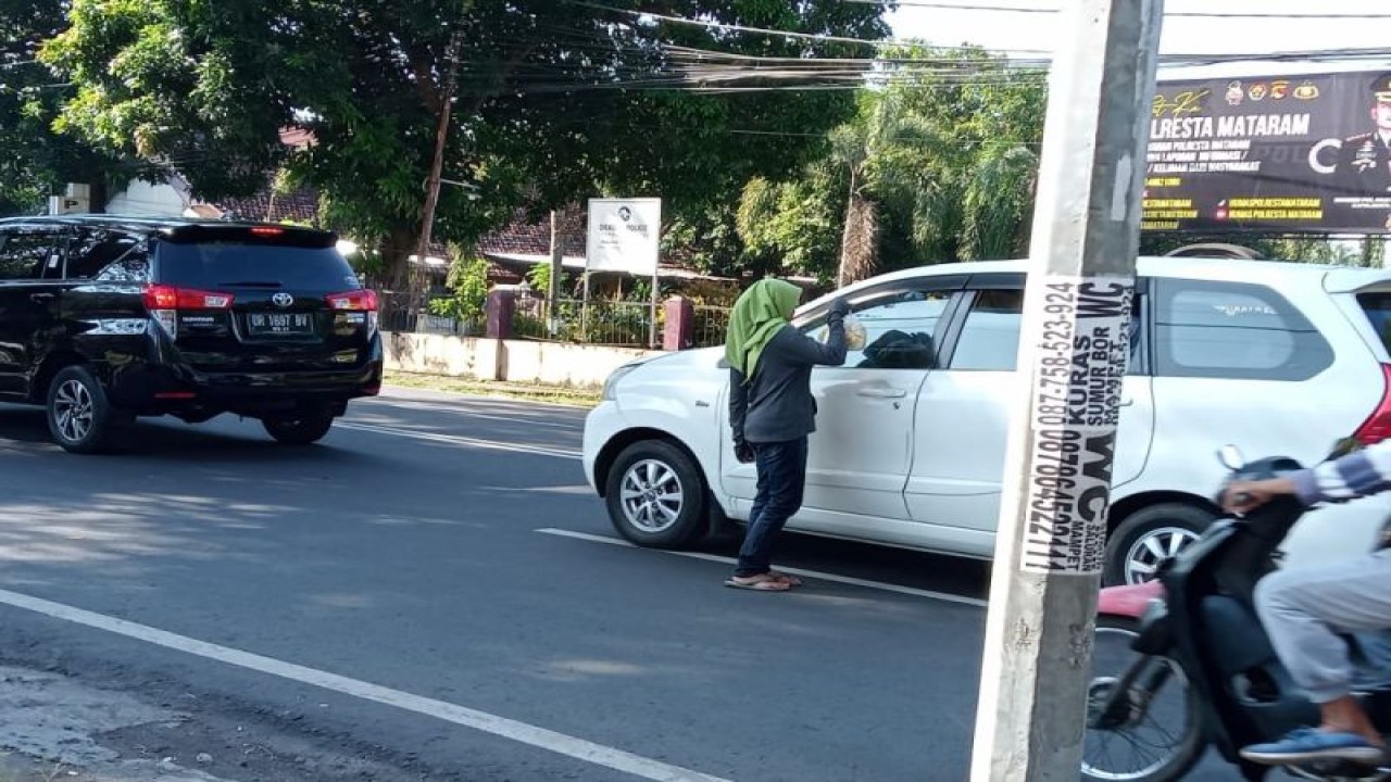 Ilustrasi: seorang ibu menjajakan jualan di Jalan Selaparang Kota Mataram, Provinsi Nusa Tenggara Barat, dinilai membahayakan baik bagi pedagang maupun pengendara. (Foto: ANTARA/Nirkomala)