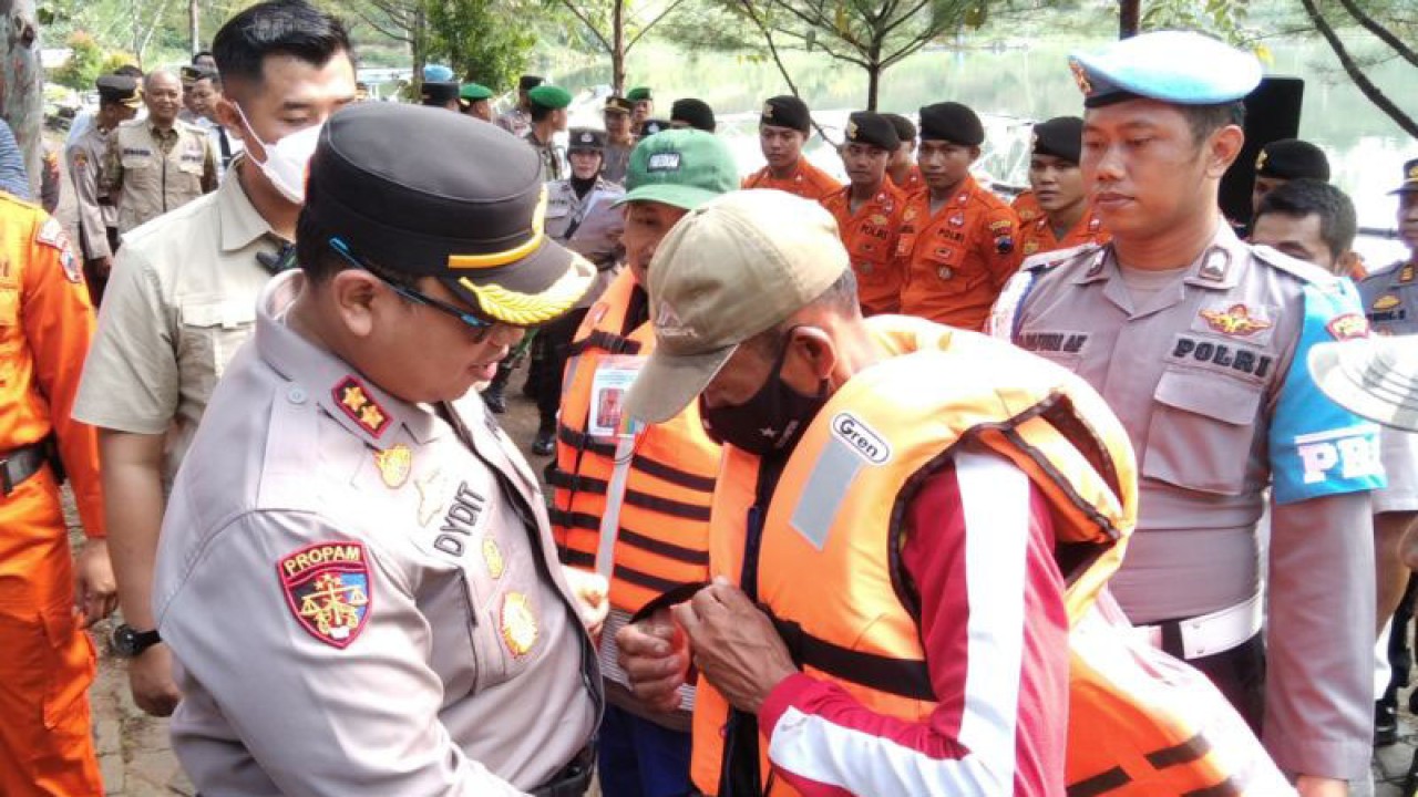 Kapolres Kudus AKBP Dydit Dwi Susanto membantu memasangkan gesper jaket pelampung yang dipakai operator perahu wisata di objek Wisata Bendungan Logung Desa Kandangmas, Kecamatan Dawe, Kabupaten Kudus, Jawa Tengah, Rabu (8/3/2023). (FOTO ANTARA/Akhmad Nazaruddin Lathif)