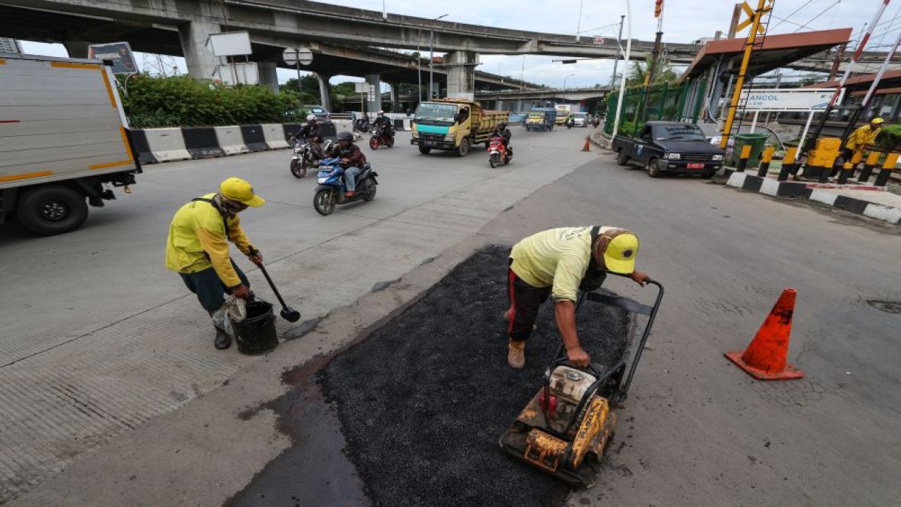Dua petugas dari Suku Dinas Bina Marga Jakarta Utara mengaspal jalan di Pademangan, Jakarta, Kamis (9/2/2023). Pemprov DKI Jakarta menargetkan perbaikan ruas jalan rusak di Ibu Kota sepanjang 115 km akan selesai pada tahun 2023. ANTARA FOTO/Prabanndaru Wahyuaji/wpa/nym.