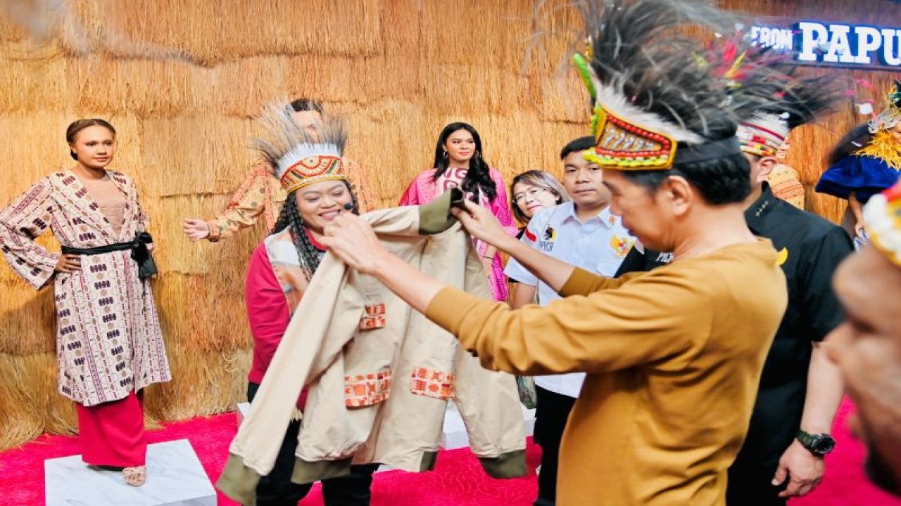 Presiden Joko Widodo (Jokowi) mendapat hadiah jaket dari seorang perancang busana asli Papua, Eunike Yunita, saat meninjau Papua di Papua Youth Creative Hub (PYCH), Jayapura, Papua, pada Selasa (21/3/2023). (ANTARA/HO-Biro Pers Sekretariat Presiden/Laily Rachev)