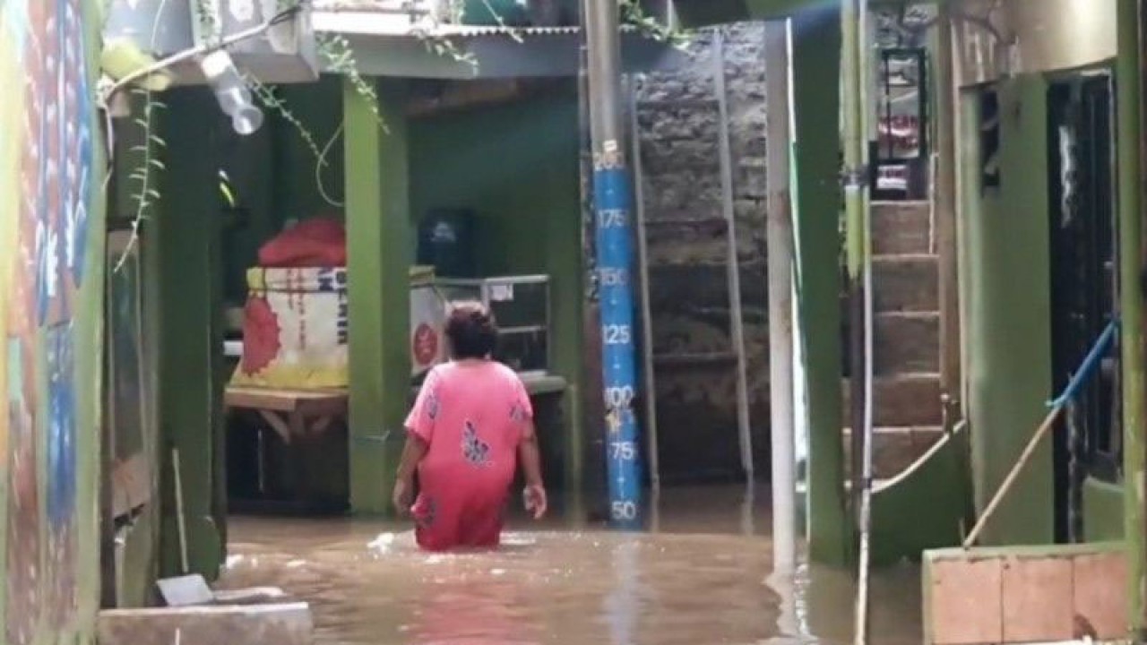 Seorang warga tengah melintasi jalan yang terendam banjir di permukiman Kebon Pala, Kelurahan Kampung Melayu, Kecamatan Jatinegara, Jakarta Timur, Selasa (14/3/2023). ANTARA/Syaiful Hakim
