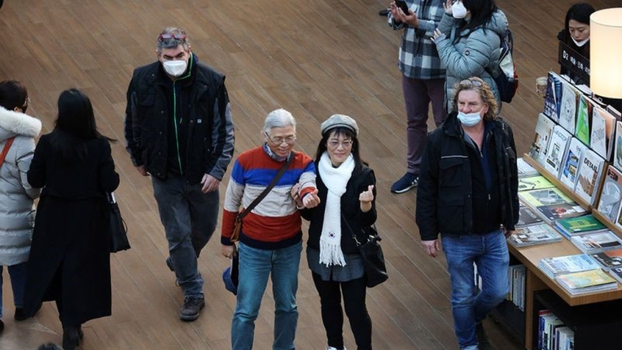 Sepasang pria dan wanita berfoto di antara pengunjung yang memakai masker untuk mencegah penularan COVID-19 di sebuah pusat perbelanjaan di Seoul, Korea Selatan, Senin (30/1/2023. Pemerintah Korea Selatan menghentikan kebijakan wajib masker di sebagian besar tempat umum dalam ruangan mulai Senin (30/1) namun masker masih harus digunakan di dalam transportasi dan fasilitas medis. ANTARA FOTO/ Reuters-Kim Hong-Ji/nym.