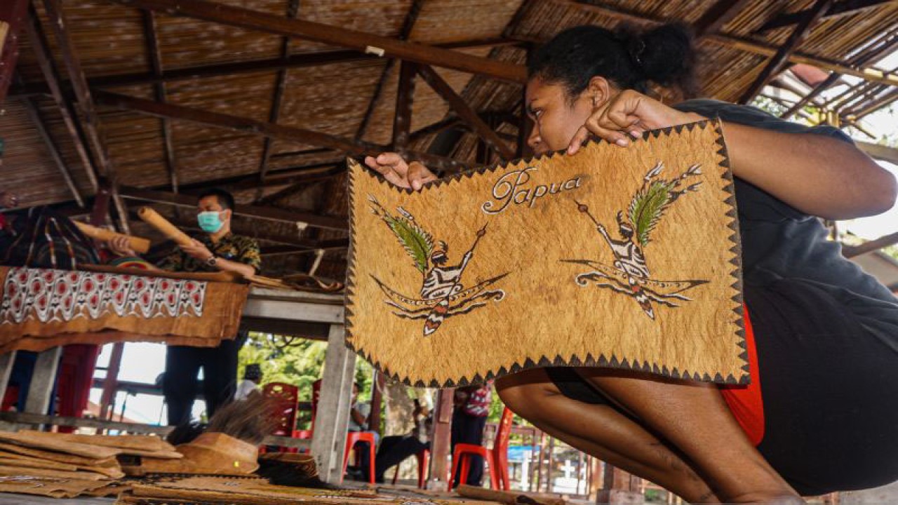 Seorang mama menata lukisan kulit kayu di Kampung Asey Pulau, Sentani Timur, Kabupaten Jayapura, Papua, Kamis (30/9/2021). Kampung tersebut dikenal sebagai lokasi dari perajin lukisan kulit kayu khas Papua dan juga sebagai pemasok suvenir lukisan kulit kayu pada perhelatan PON Papua. ANTARA FOTO/Indrayadi TH/pras.