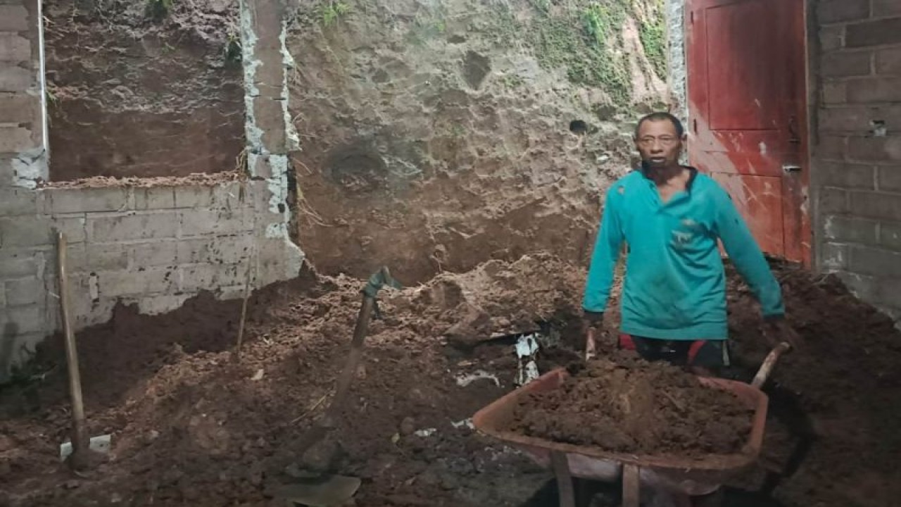 Warga menyingkirkan material longsor yang menyebabkan tembok rumahnya rusak berat di Desa Botoputih, Trenggalek, Senin (27/3/2023) (ANTARA/HO-BPBD Trenggalek)