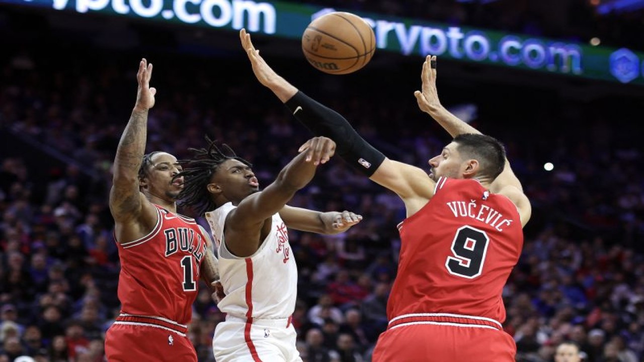 Pebasket Philadelphia 76ers Tyrese Maxey (tengah) berupaya melewati hadangan dua pebasket Chicago Bulls, DeMar DeRozan (kiri) dan Nikola Vucevic (kanan) saat pertandingan NBA kedua tim di Wells Fargo Center, Philadelphia, Pennsylvania, Senin (20/3//2023) waktu setempat. (Getty Images via AFP/TIM NWACHUKWU)