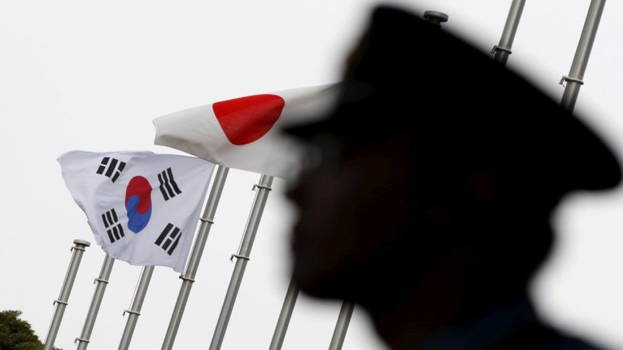FOTO FILE: Seorang petugas polisi berjaga dekat bendera nasional Jepang dan Korea Selatan di hotel, tempat kedutaan Korea Selatan di Jepang mengadakan resepsi untuk menandai peringatan 50 tahun normalisasi hubungan antara Seoul dan Tokyo, di Tokyo 22 Juni 2015. REUTERS/Toru Hanai/ File Foto