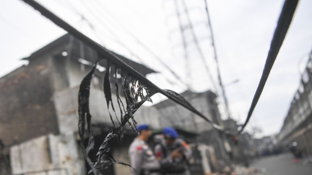 Anggota Polri berjaga di permukiman yang hangus terbakar pascakebakaran Depo Pertamina Plumpang di Jalan Koramil, Rawa Badak Selatan, Koja, Jakarta, Sabtu (4/3/2023). (ANTARA FOTO/M Risyal Hidayat/foc)