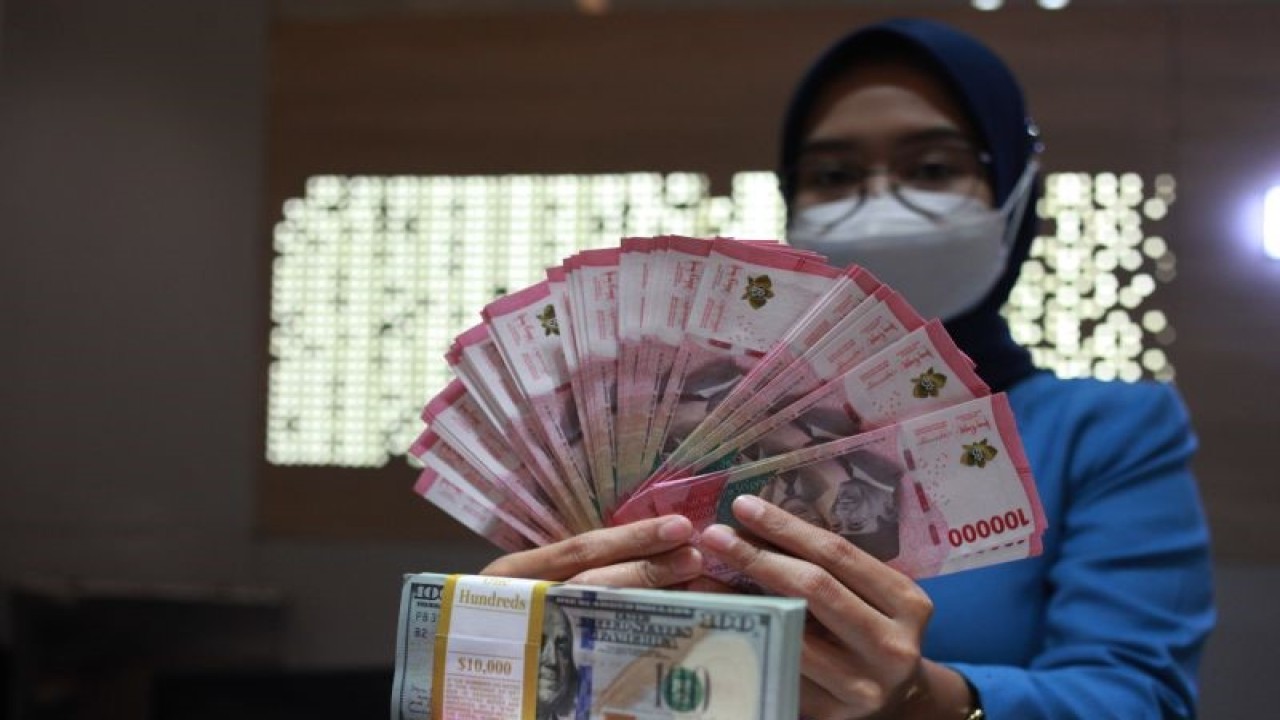 Petugas menunjukkan uang dolar AS dan uang rupiah di salah satu kantor cabang PT. Bank Mandiri Persero Tbk, Jakarta, Selasa (31/1/2023). Nilai tukar (kurs) rupiah yang ditransaksikan antarbank di Jakarta merosot 33 poin atau 0,22 persen ke posisi Rp15.003 per dolar AS dibandingkan posisi pada penutupan perdagangan sebelumnya Rp14.970 per dolar AS. ANTARA FOTO/Reno Esnir/tom. (ANTARA FOTO/RENO ESNIR)