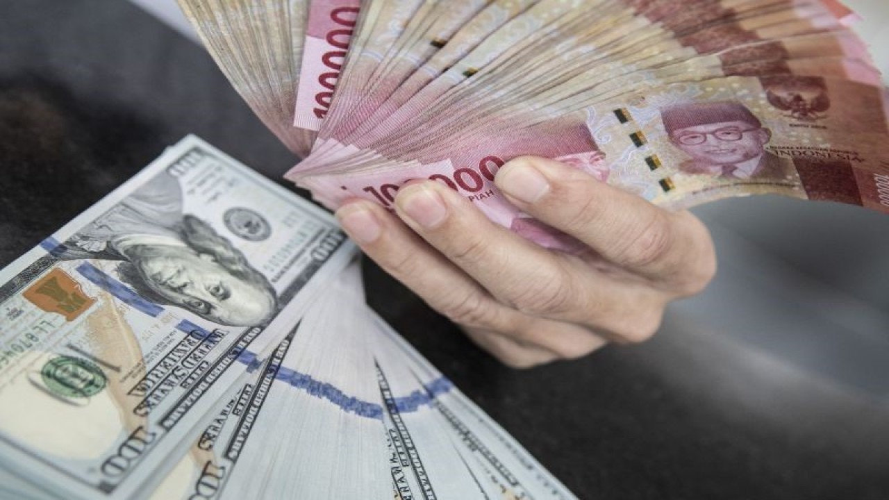 Petugas menunjukan uang pecahan rupiah dan dolar AS di gerai penukaran mata uang asing VIP (Valuta Inti Prima) Money Changer, Jakarta, Selasa (3/1/2023). ANTARA FOTO/Muhammad Adimaja/foc.