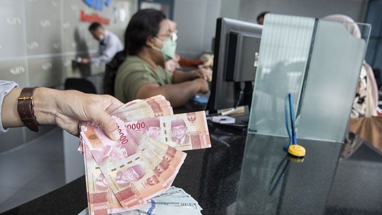 Petugas menunjukan uang pecahan rupiah dan dolar AS di gerai penukaran mata uang asing VIP (Valuta Inti Prima) Money Changer, Jakarta, Selasa (3/1/2023). ANTARA FOTO/Muhammad Adimaja/foc/aa.