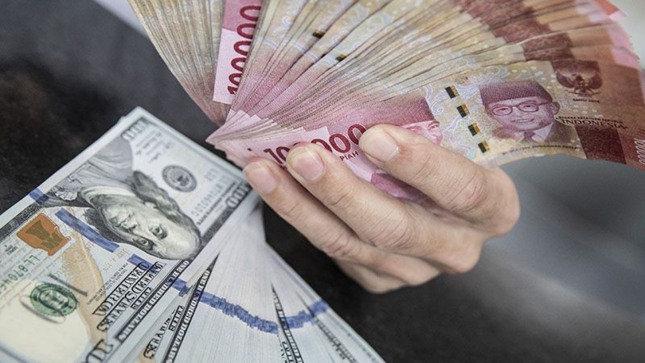 Ilustrasi - Petugas menunjukan uang pecahan rupiah dan dolar AS di gerai penukaran mata uang asing VIP (Valuta Inti Prima) Money Changer, Jakarta. ANTARA FOTO/Muhammad Adimaja/foc/pri. (ANTARA FOTO/MUHAMMAD ADIMAJA)