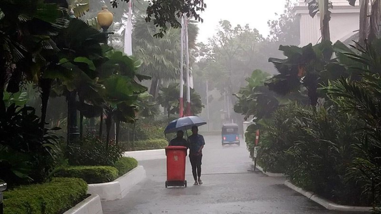 Petugas kebersihan melintas di tengah guyuran hujan deras di Balai Kota Jakarta, Jumat (24/2/2023). ANTARA/Dewa Ketut Sudiarta Wiguna/aa.